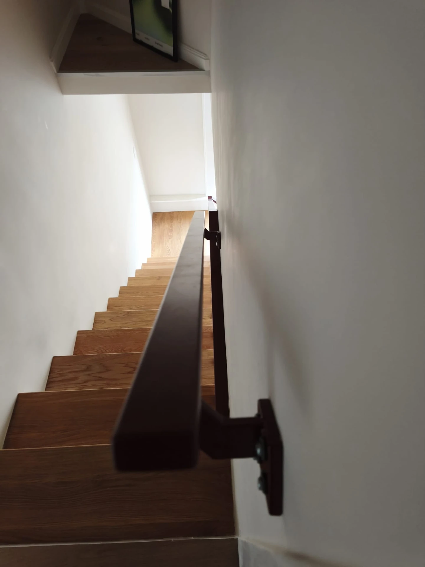 Stalen wandhandgreep in wijnrood RAL 3005 langs het trapgat, bijpassend bij de maatwerk balustrade in Amsterdam-West